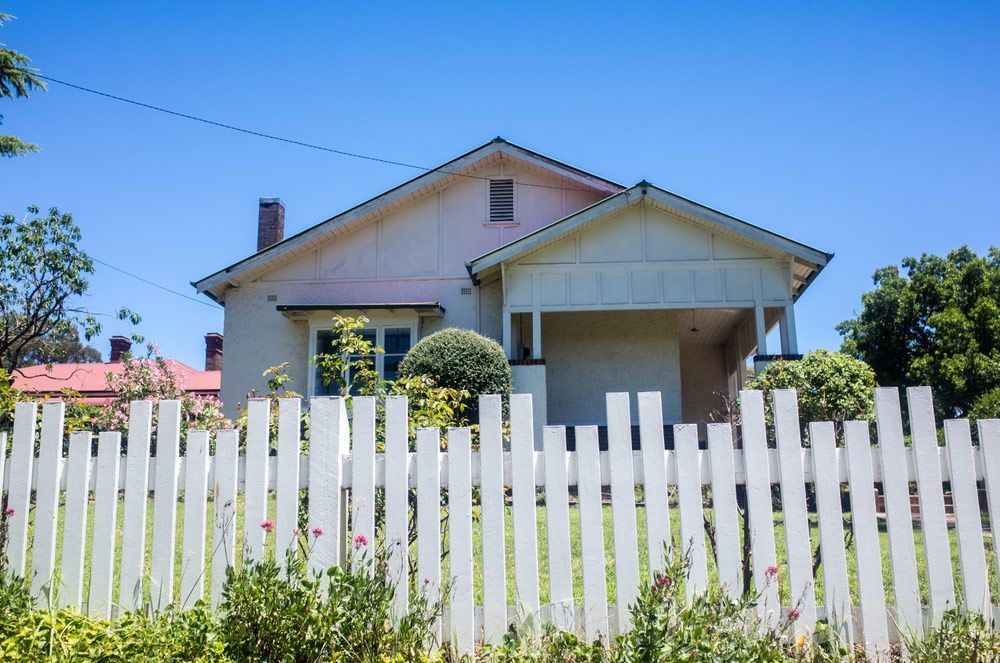 A White Picket Fence is in Front of a House — Clarence Property Consultants In Maclean, NSW