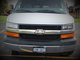 Front view of a silver Chevrolet van with a black grille and orange turn signals