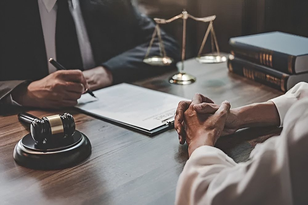 Lawyer and client at desk with gavel, documents and scales of justice.