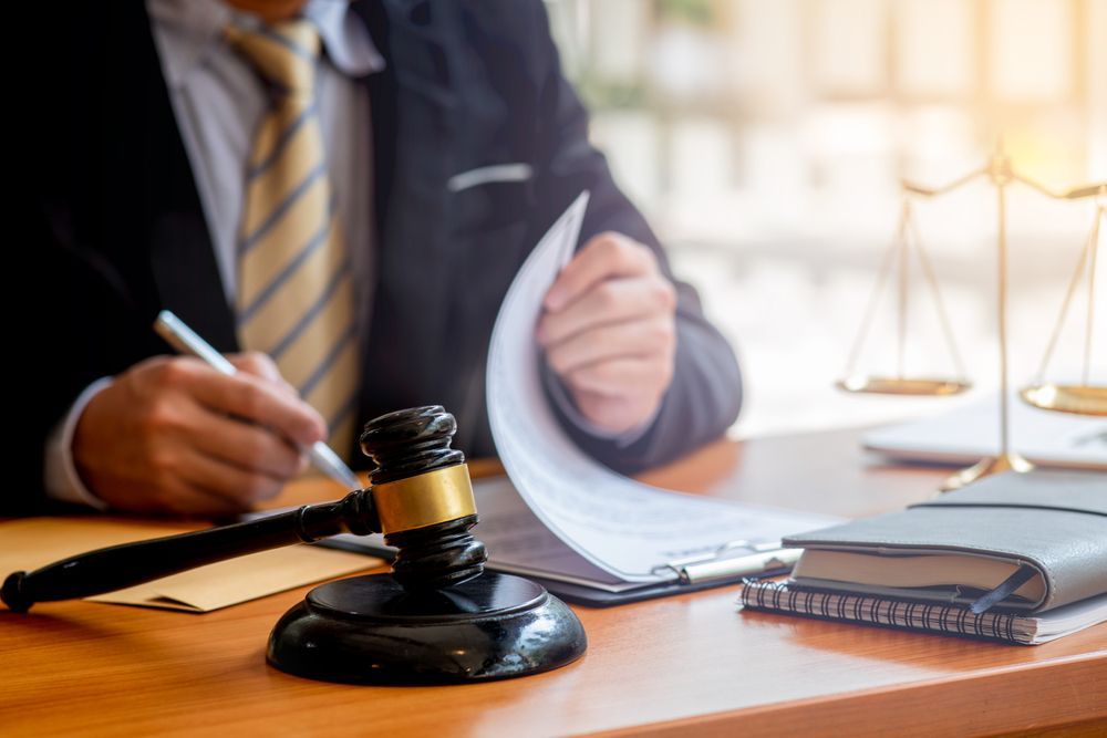 Lawyer signing documents with gavel, scales of justice, and notebook on a desk — Bradley Solicitors in Larrakeyah, NT