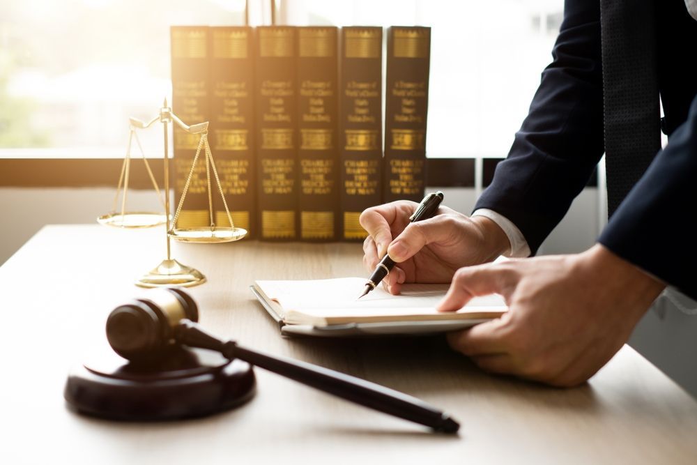Lawyer signing documents at a desk with gavel, scales, and law books in the background — Bradley Solicitors in Larrakeyah, NT