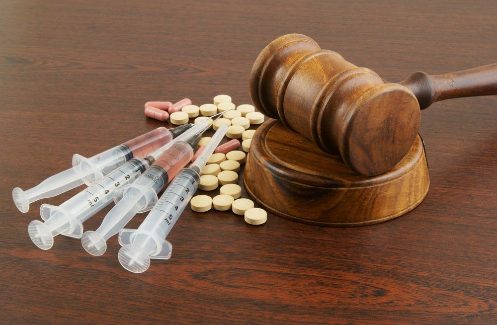 Gavel on Sound Block Next to Syringes and Pills on a Wooden Surface — Bradley Solicitors in Larrakeyah, NT