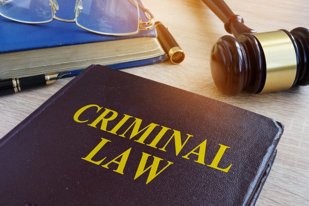 Book With Criminal Law Title, Glasses, Pen, and Gavel on a Wooden Surface — Bradley Solicitors in Larrakeyah, NT