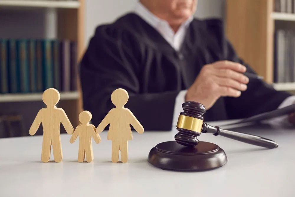 Wooden Family Figures Near a Gavel in a Courtroom With a Judge — Bradley Solicitors in Larrakeyah, NT