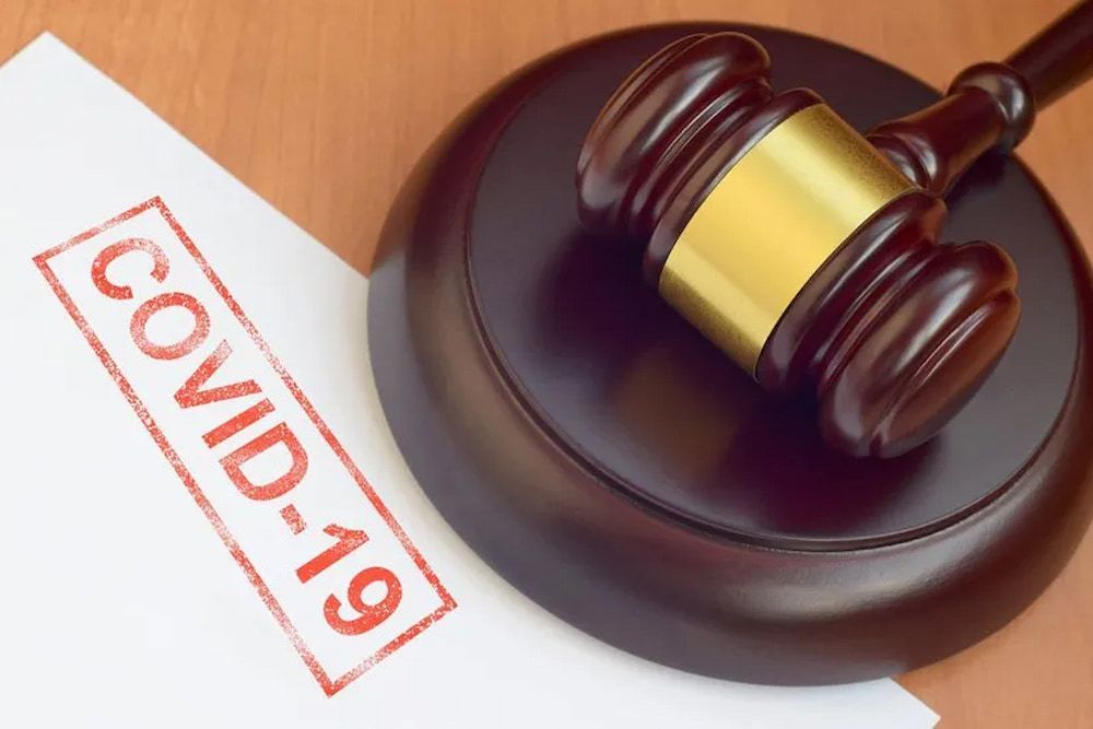 Gavel on a Wooden Block Next to a Paper Stamped With COVID-19 — Bradley Solicitors in Larrakeyah, NT