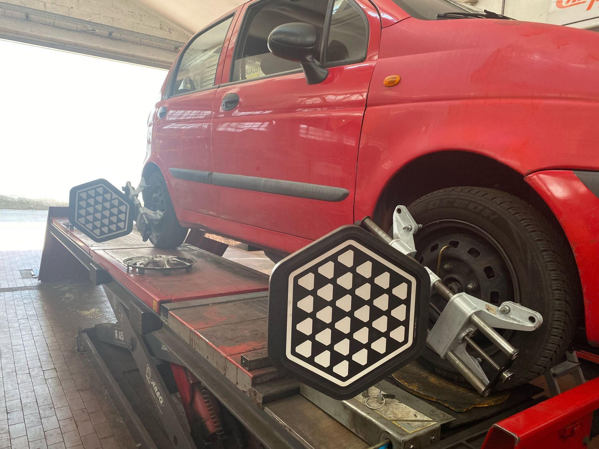 Un SUV rosso su un banco di allineamento in un'officina, con i bersagli di allineamento delle ruote fissati alle ruote stesse.