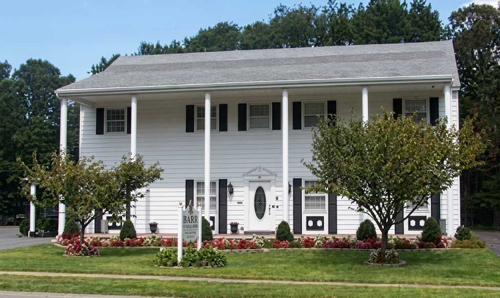 Front of Barr Funeral Home with white columns and a landscaped lawn