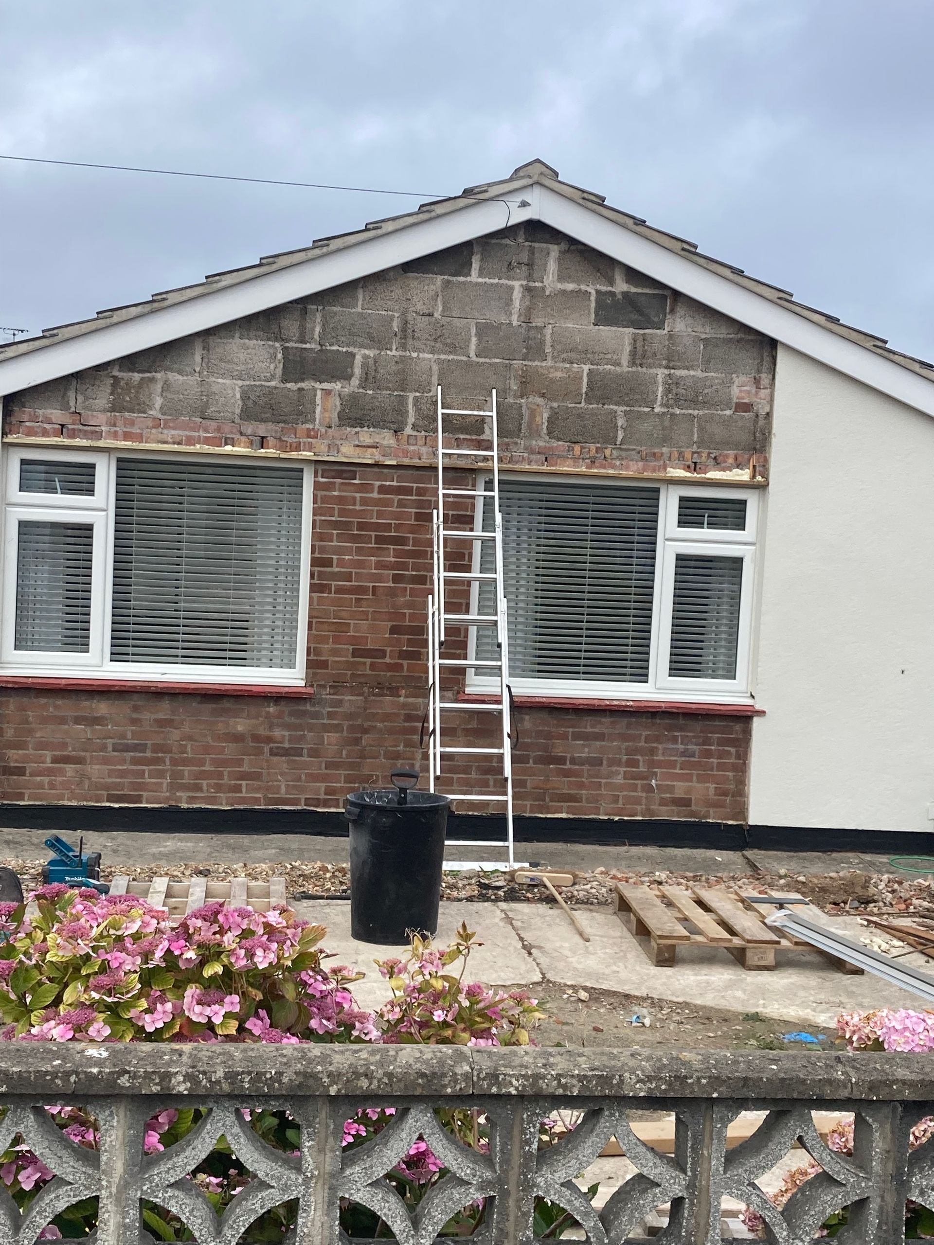 A ladder is sitting in front of a brick house.