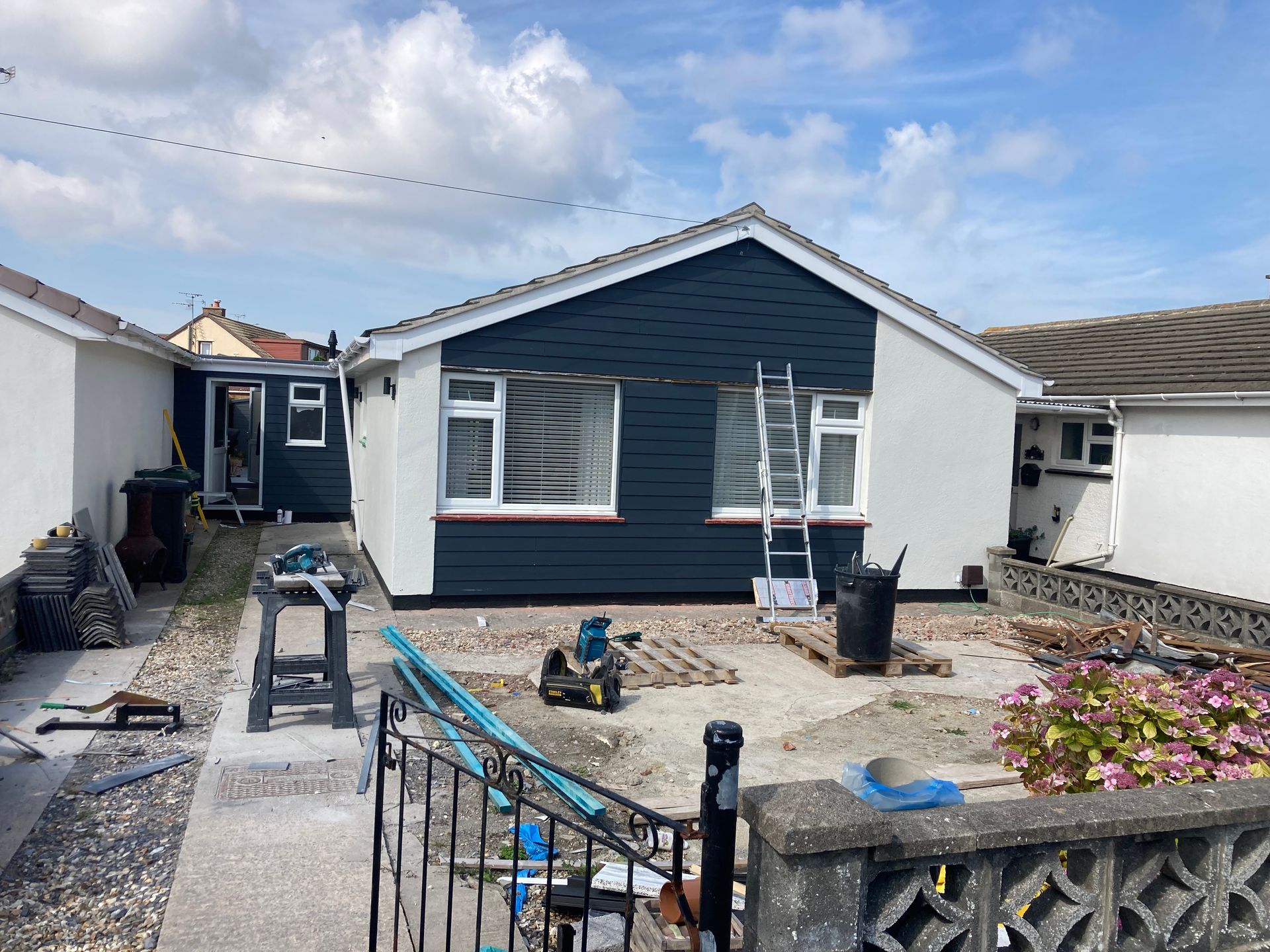 A house with a blue siding and white trim is being painted.