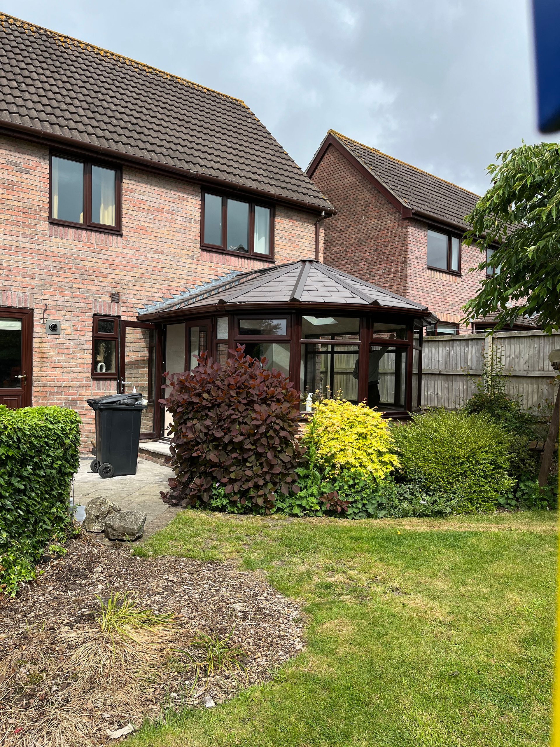 A brick house with a conservatory and a garden in front of it.