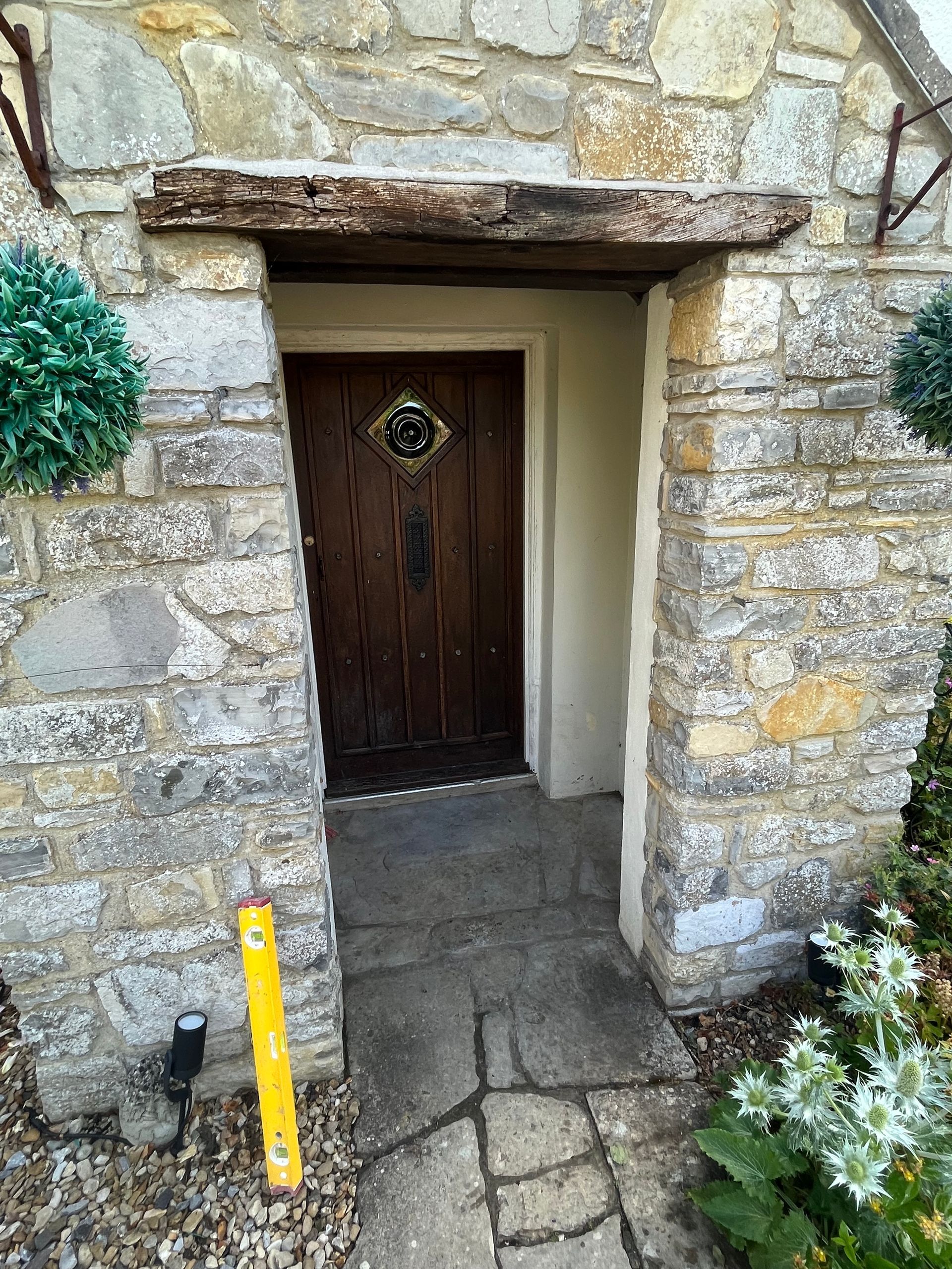 A stone wall with a wooden door and a yellow level in front of it.