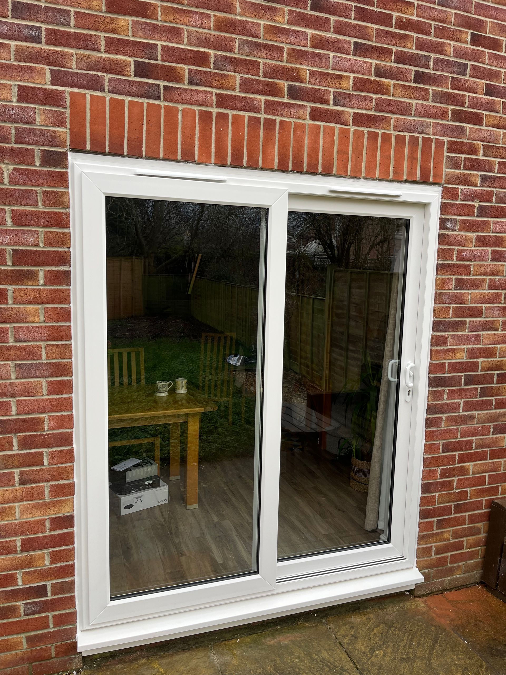 A white sliding glass door is open to a living room with a table and chairs.