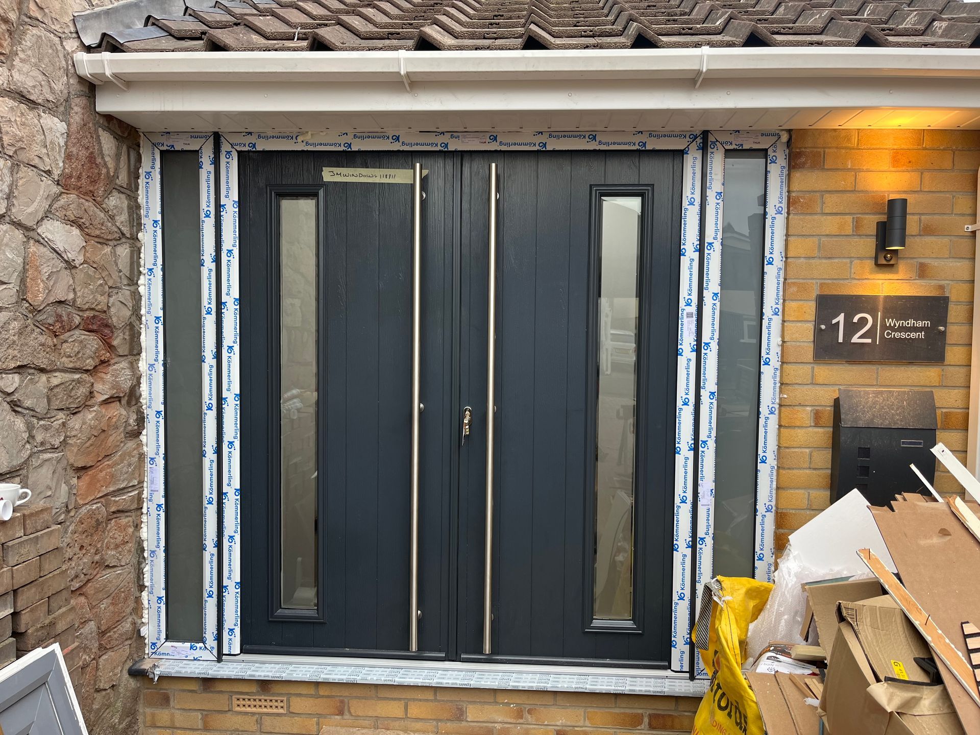 A black front door is being installed on a brick house.