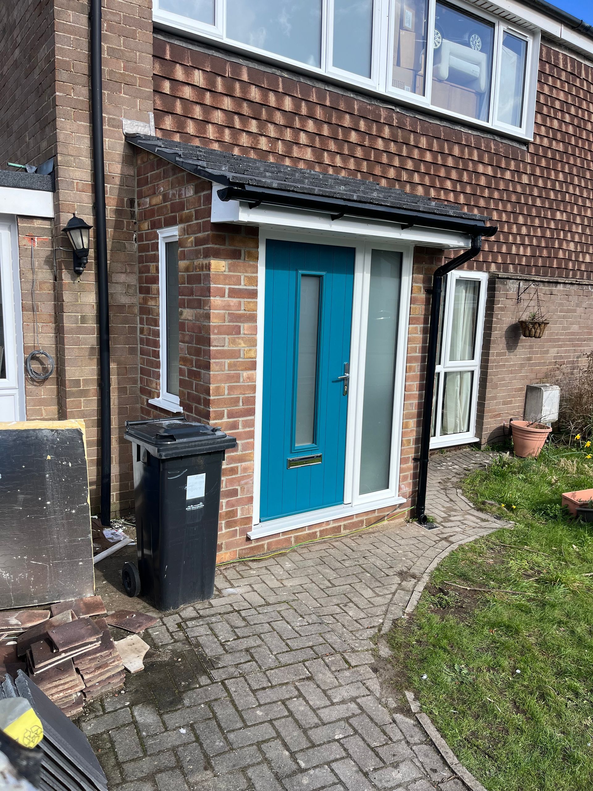 A blue door is on the side of a brick house.