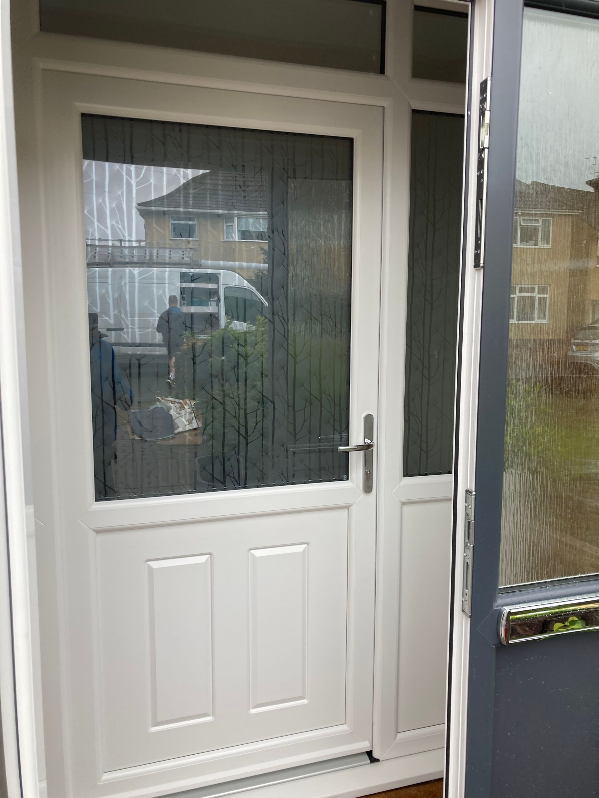 A white door with a large glass window is open to a house.