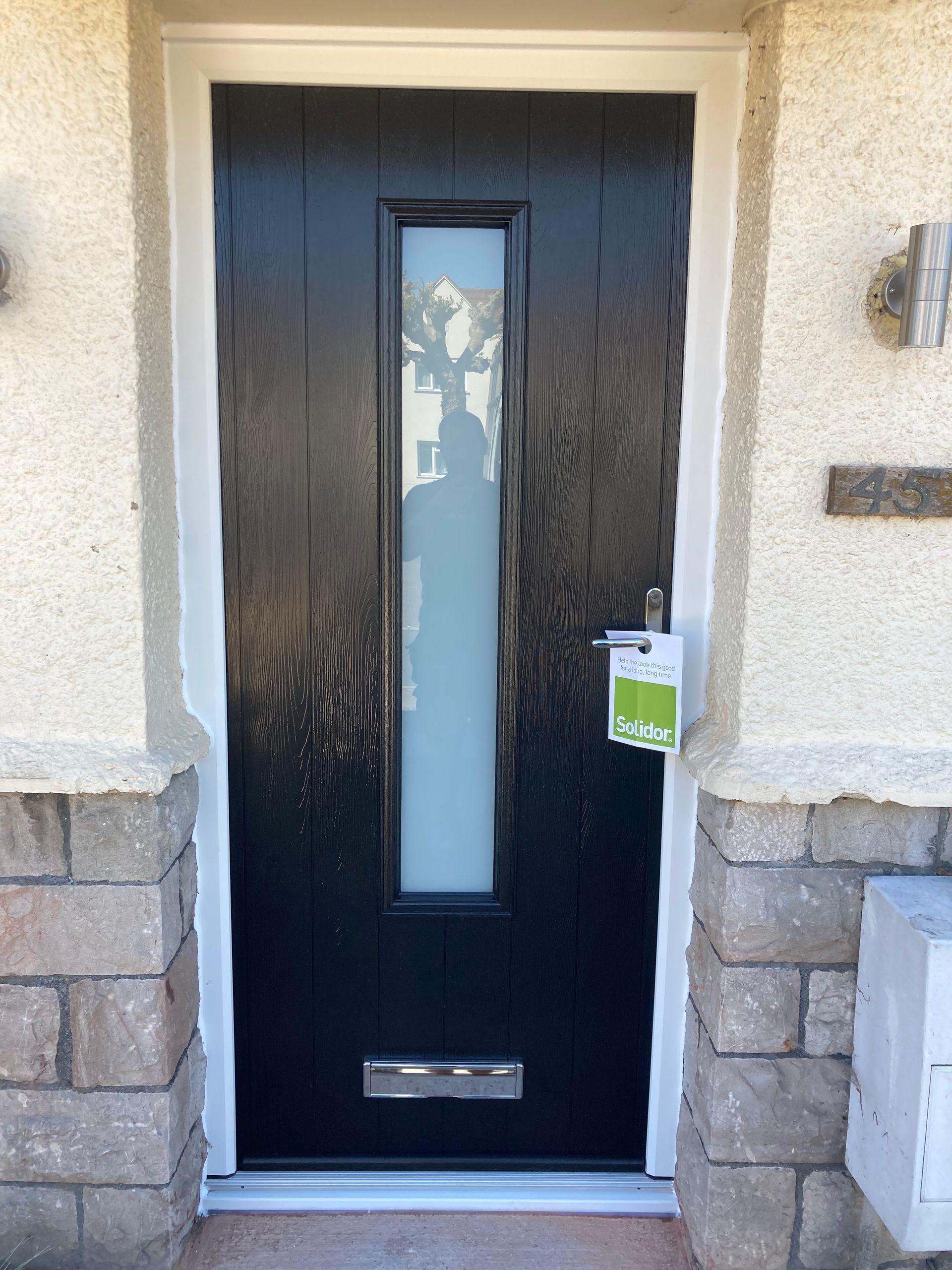 A black door with a white window is on a brick building.