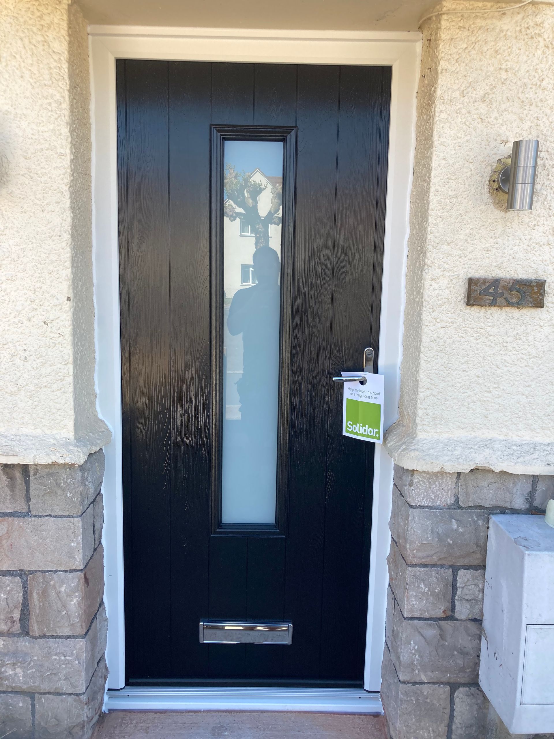 A black front door with a white window and a sign on it.