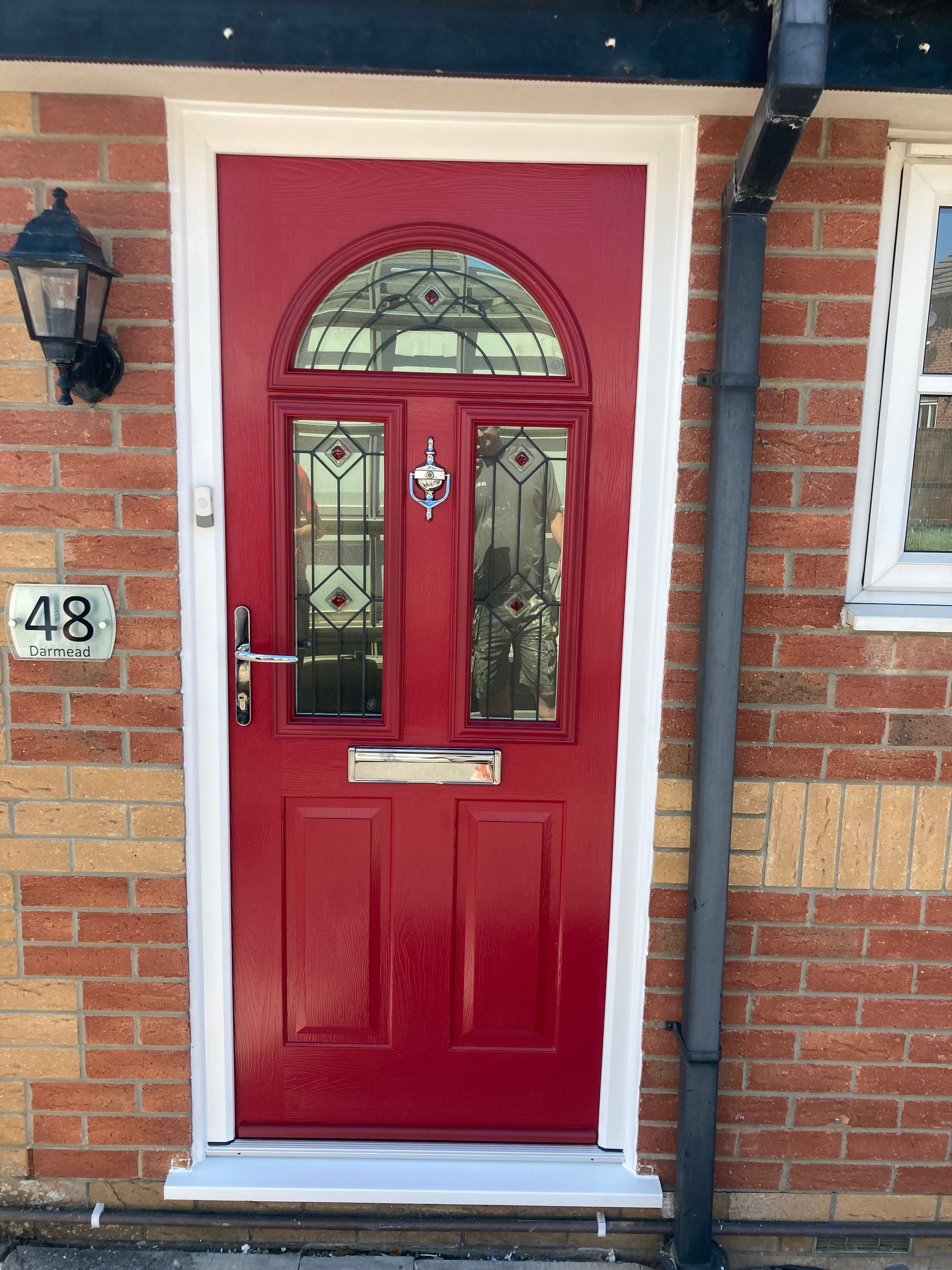 A red door with a white trim is on a brick building.
