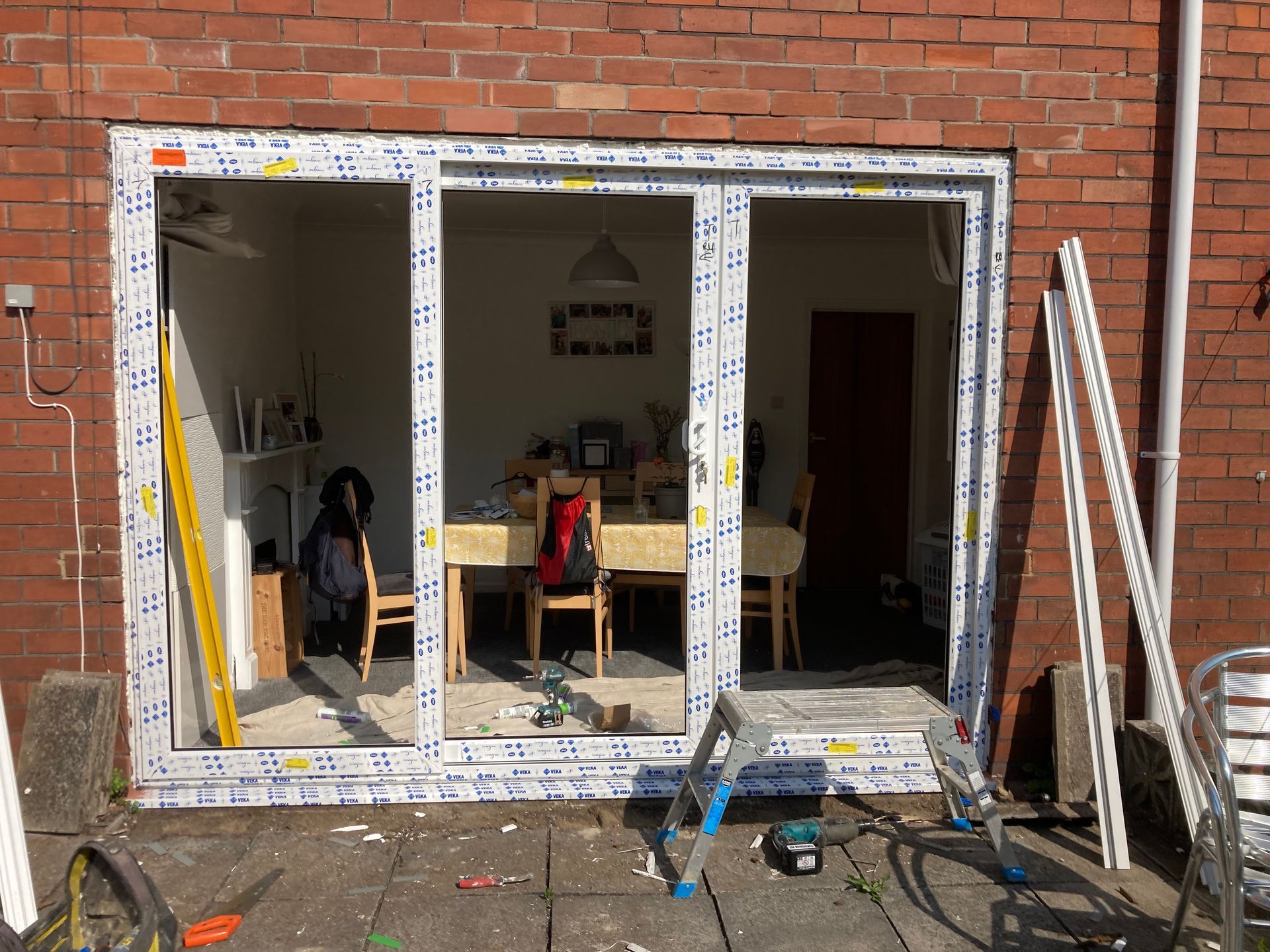 A sliding glass door is being installed in a brick building.