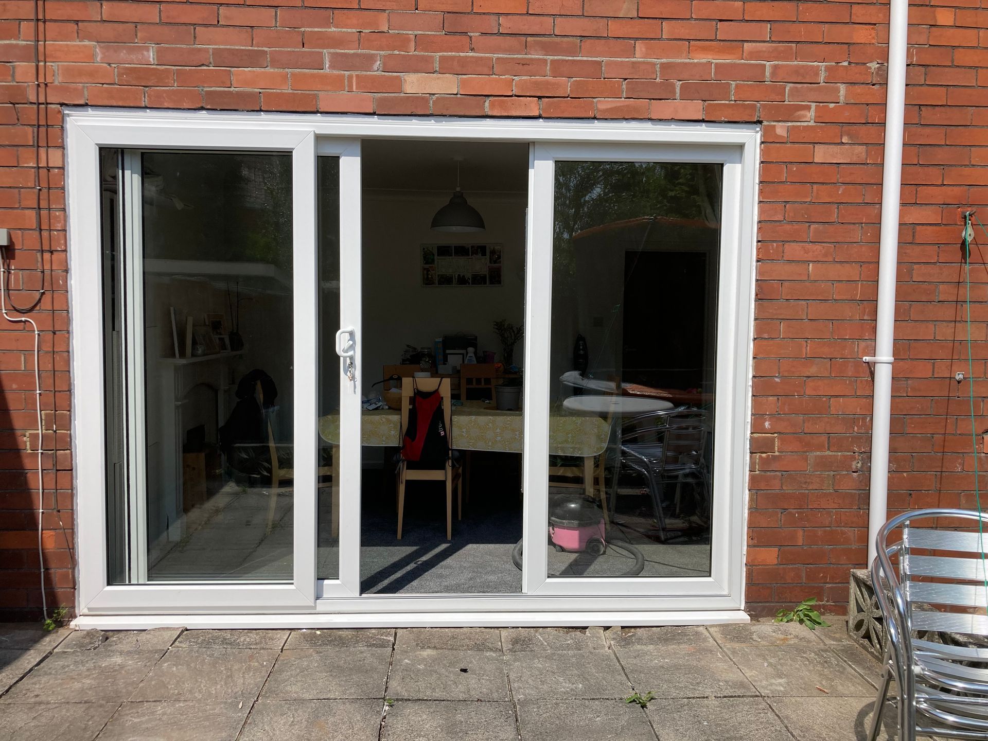 A white sliding glass door is open to a dining room with a table and chairs.