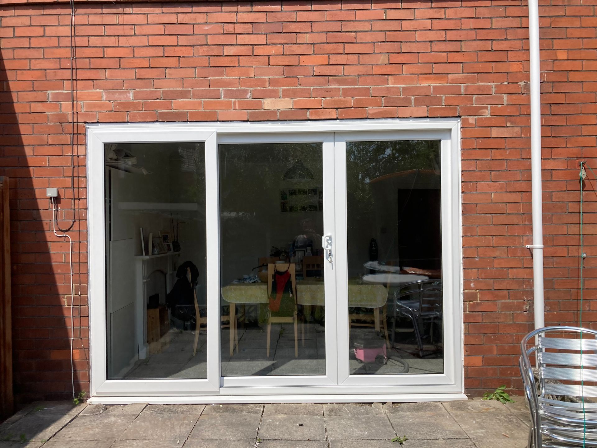 A brick building with a white sliding glass door leading to a patio.
