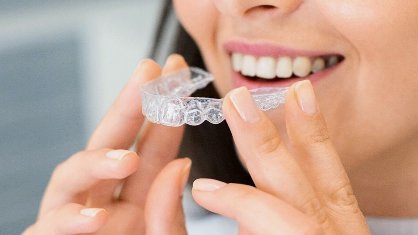 Dentist examining a smiling patient in a dental chair with tools and gloved hands
