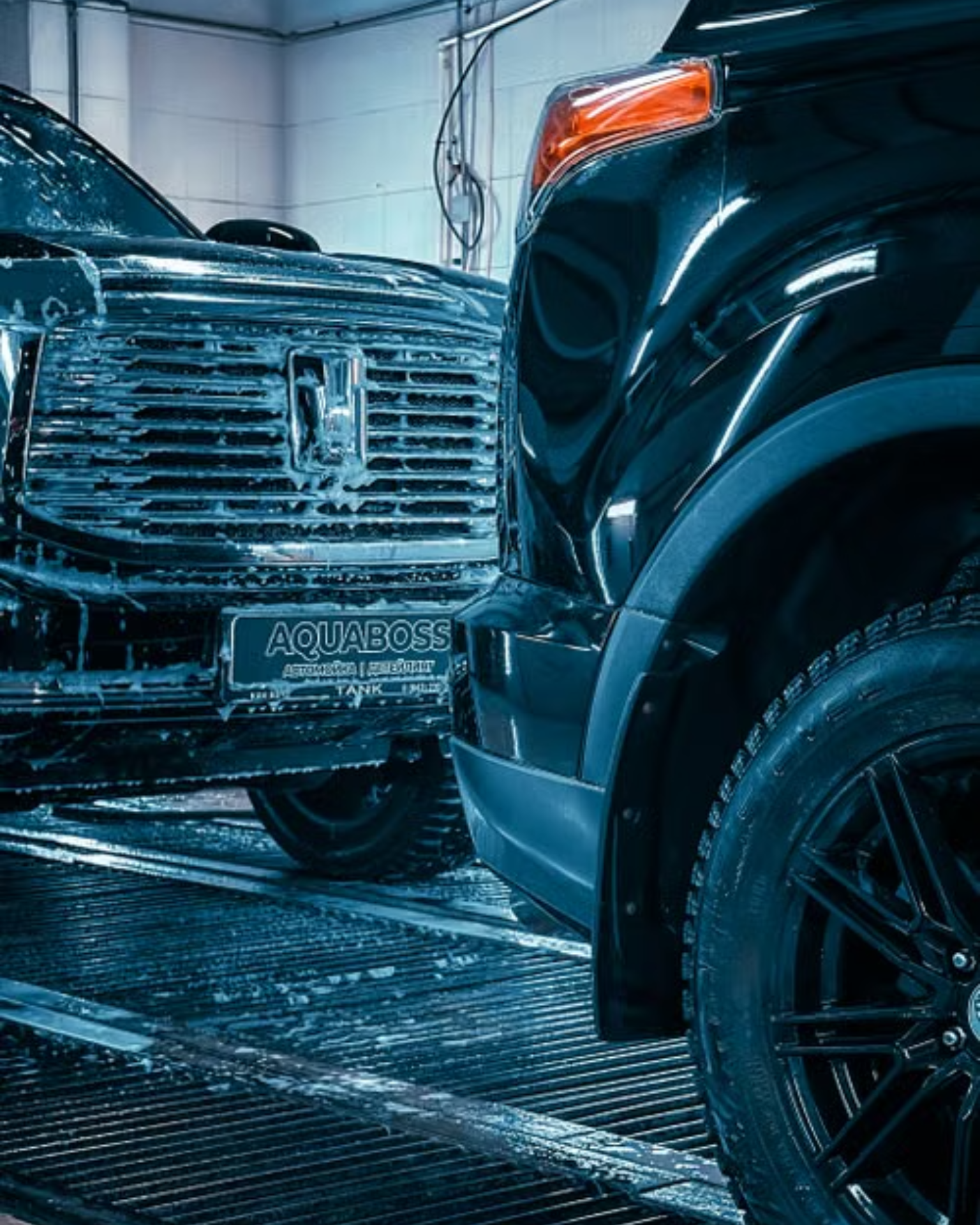 A man with tattoos is washing a car in a garage.