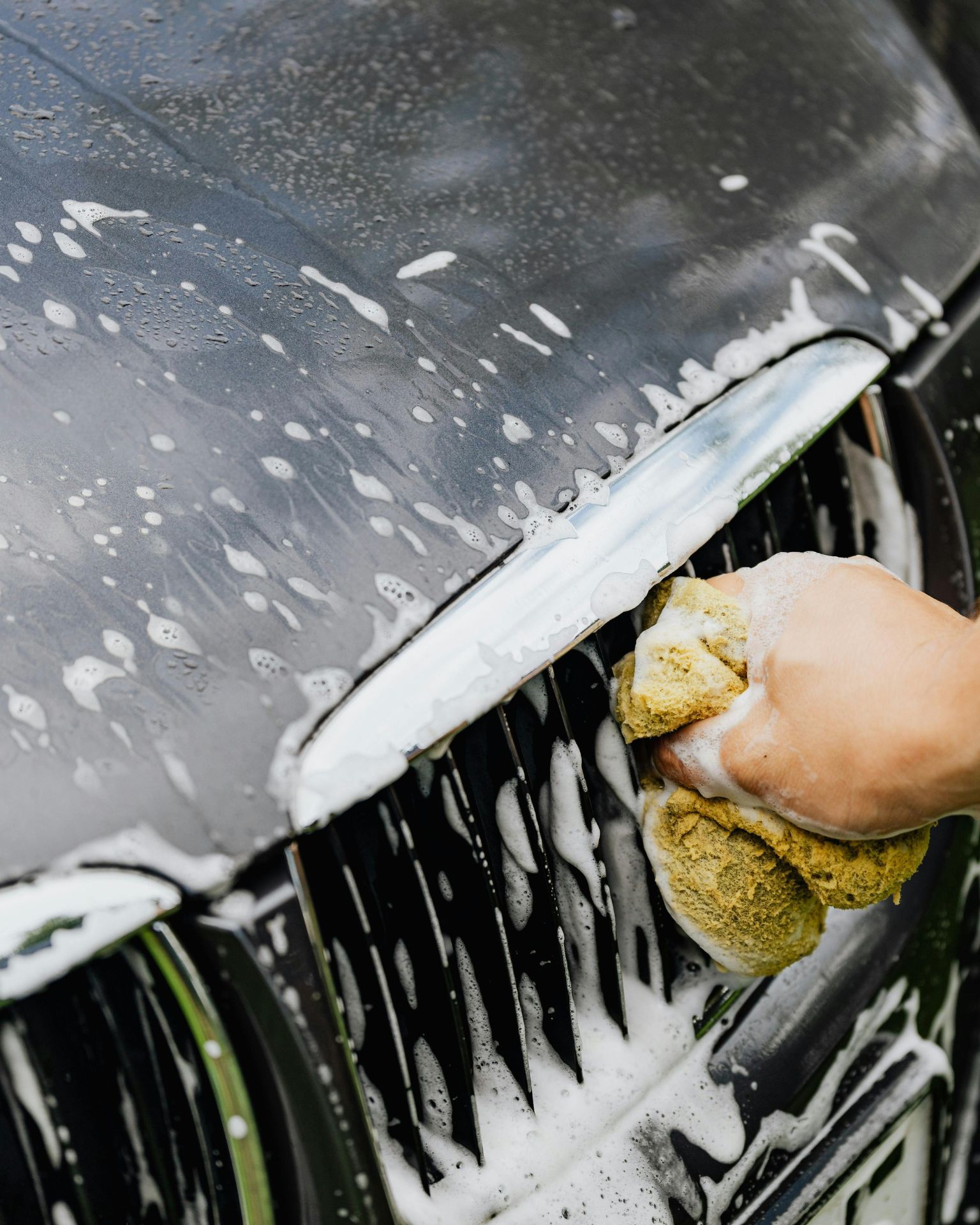A man with tattoos is washing a car in a garage.
