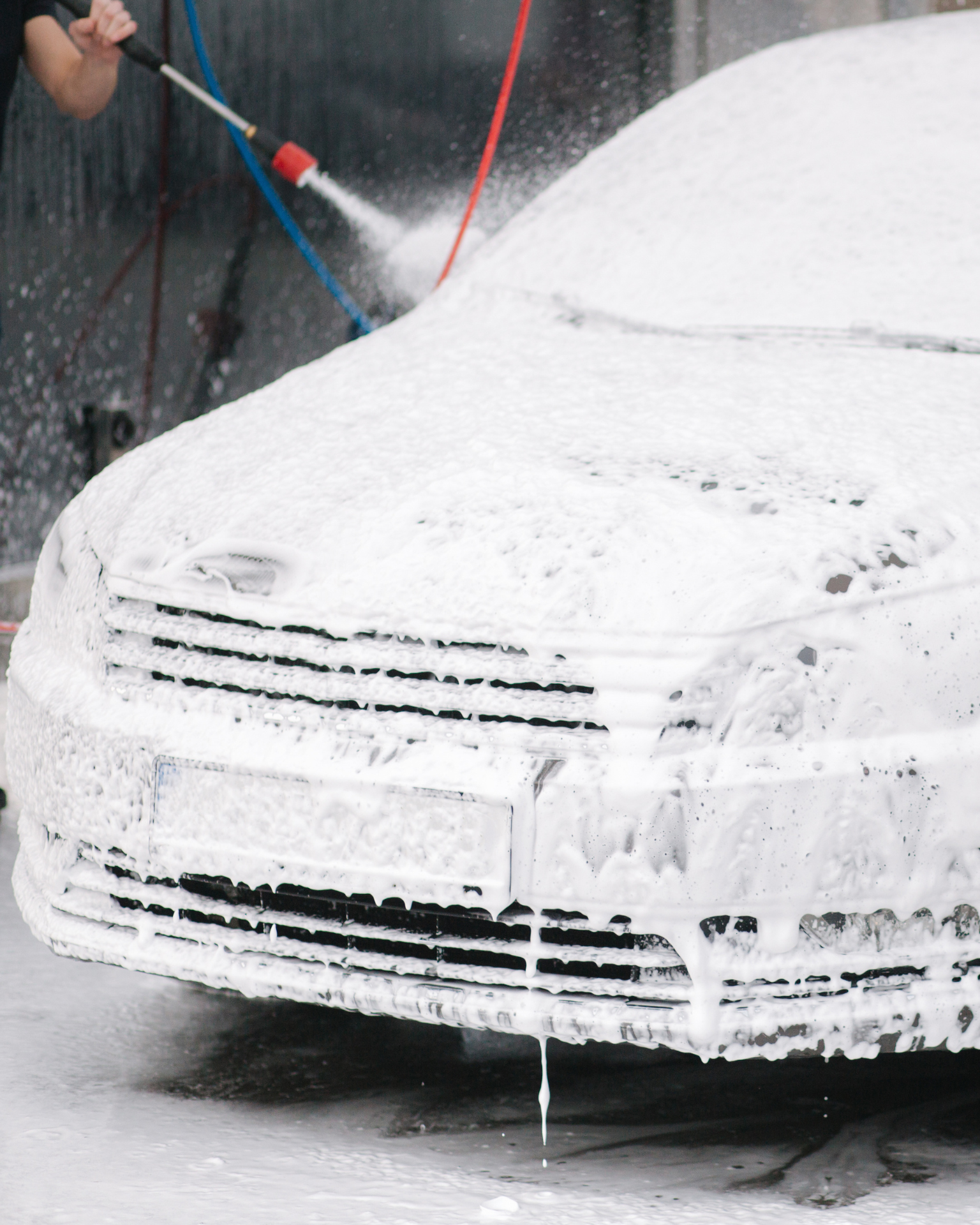 A man with tattoos is washing a car in a garage.