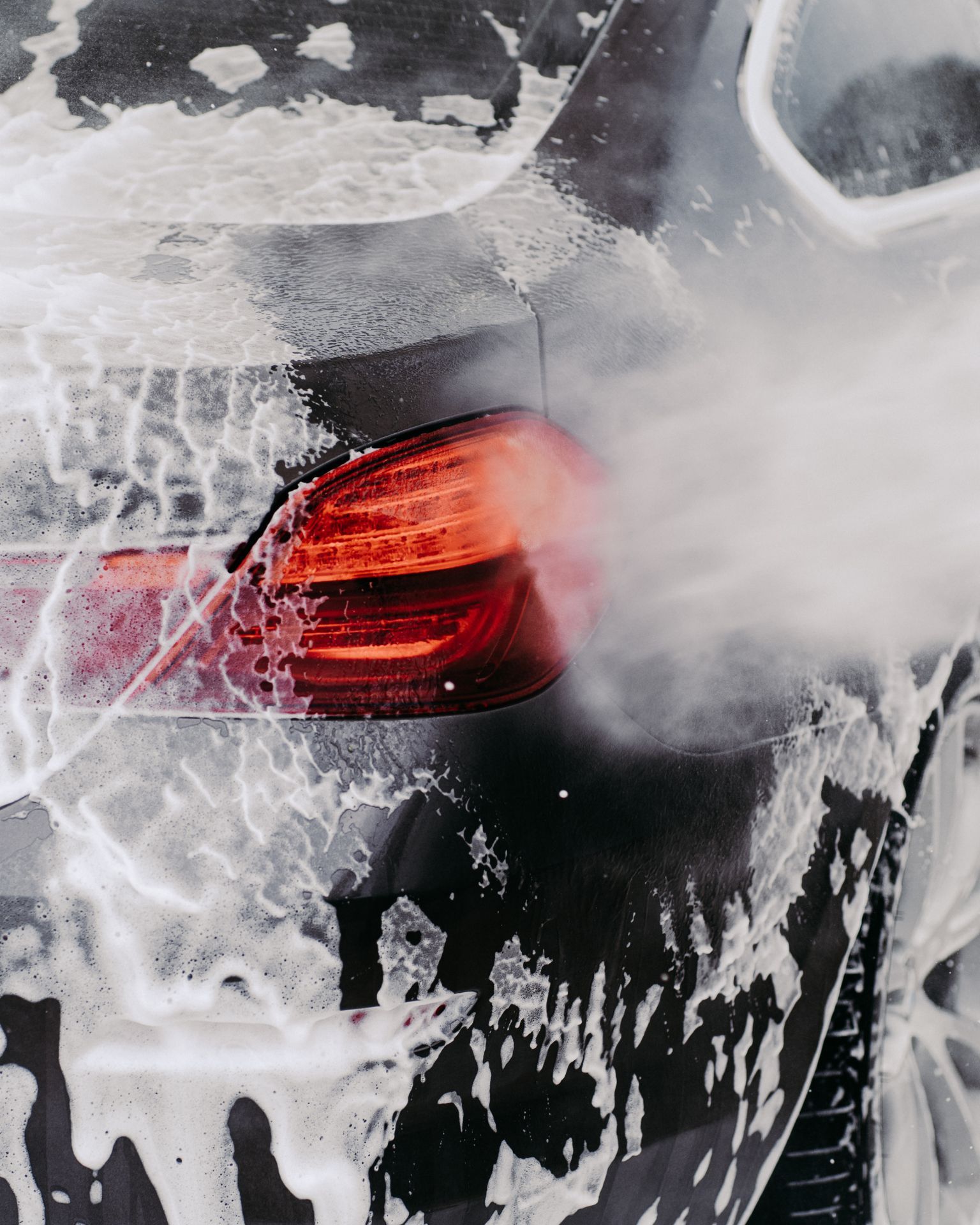 A man with tattoos is washing a car in a garage.