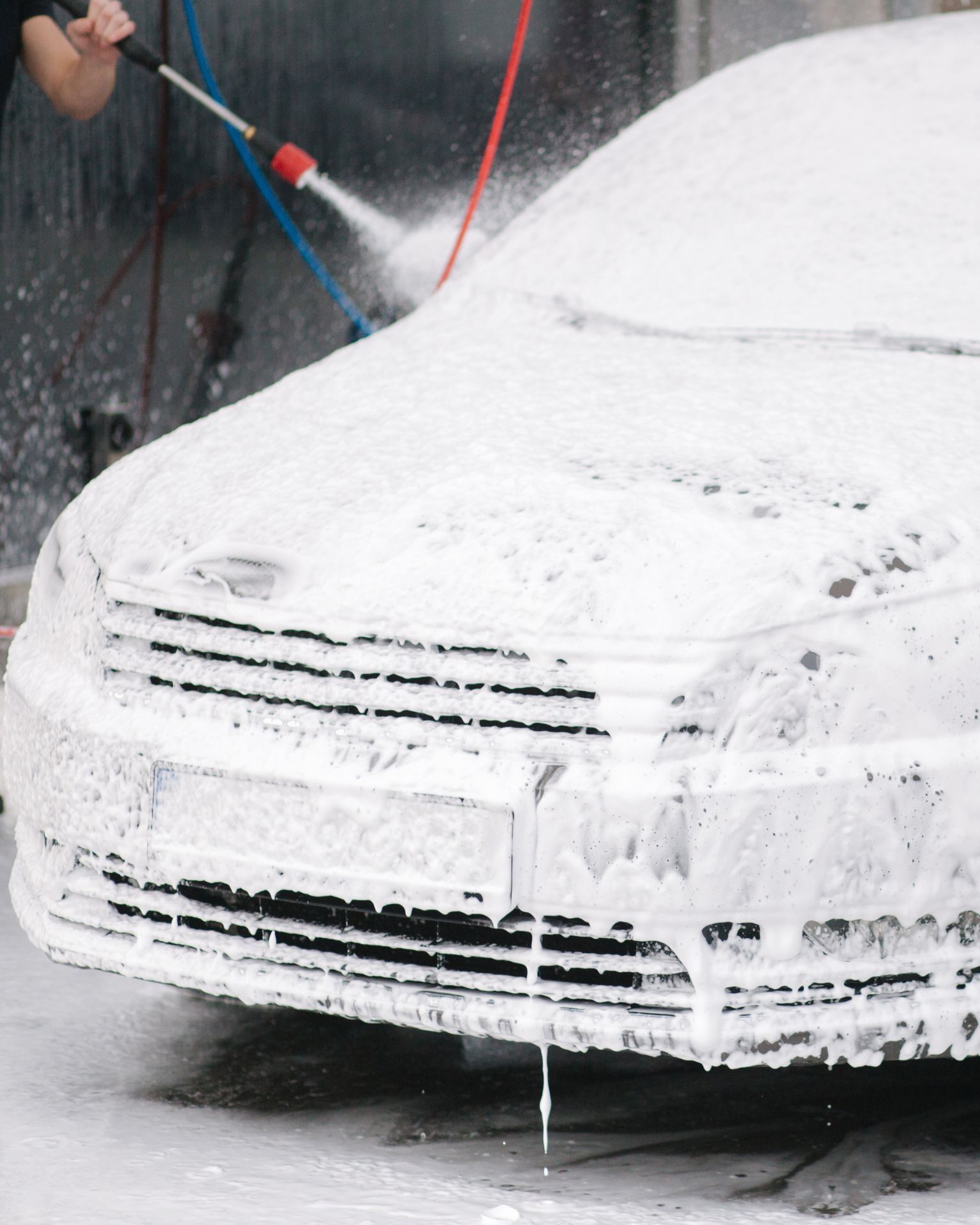 A man with tattoos is washing a car in a garage.