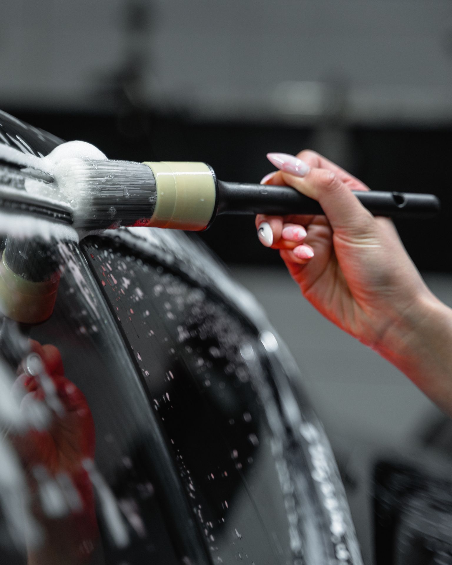 A man with tattoos is washing a car in a garage.