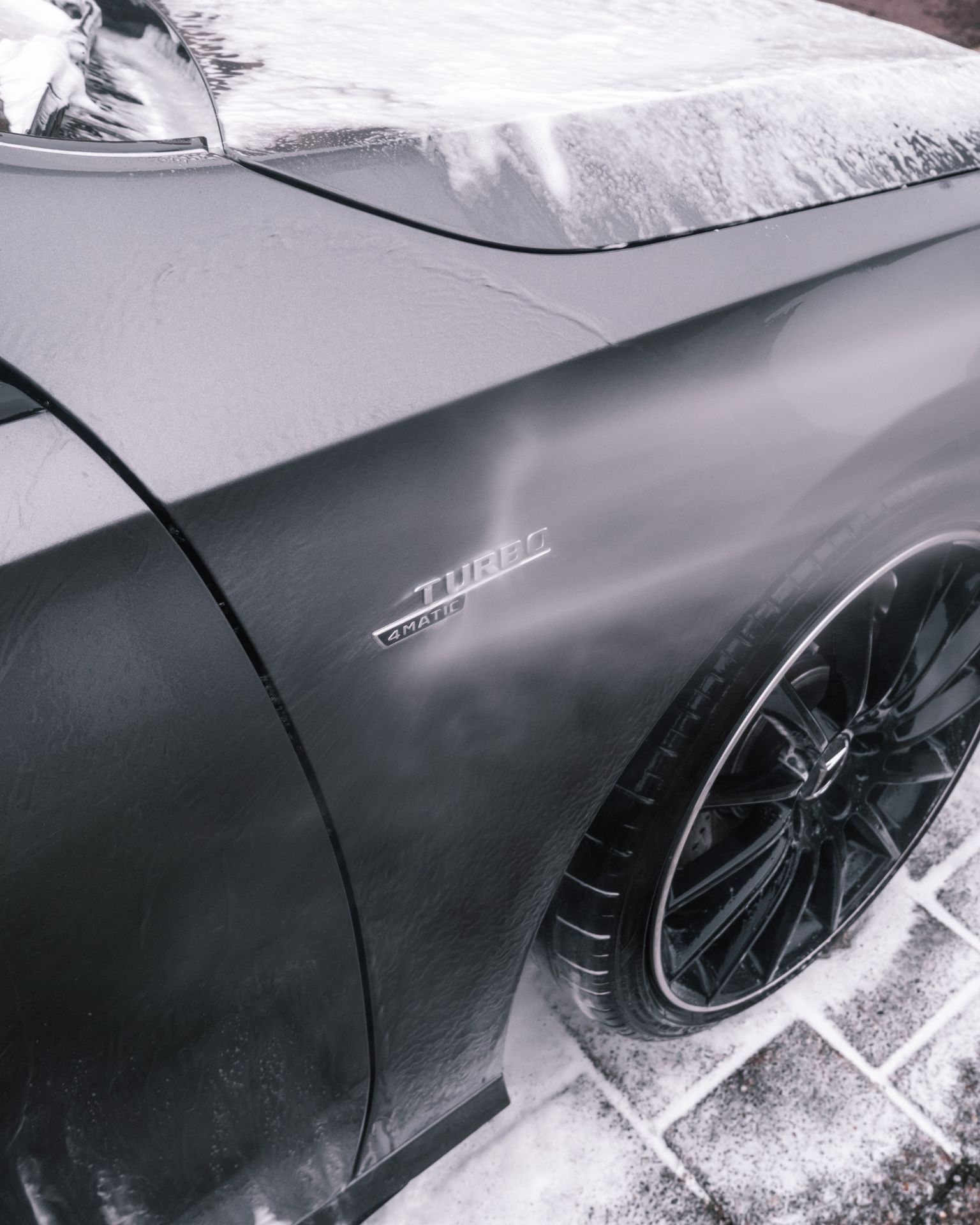 A man with tattoos is washing a car in a garage.