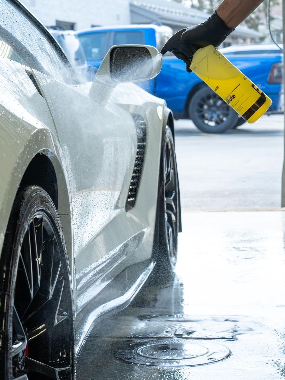A car is being washed with a high pressure washer in a garage.