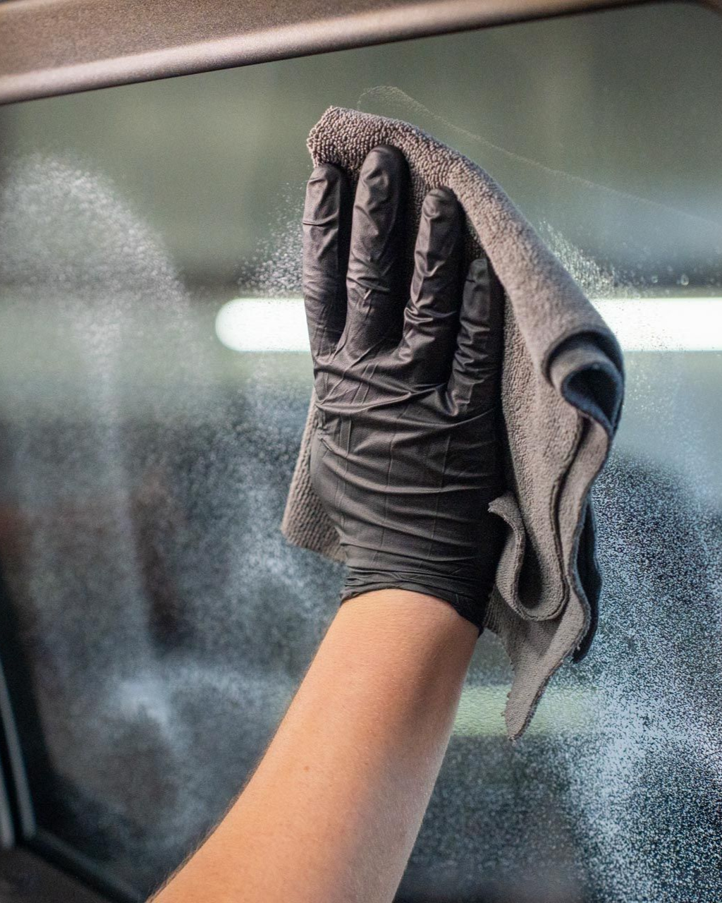A car is being washed with a high pressure washer in a garage.