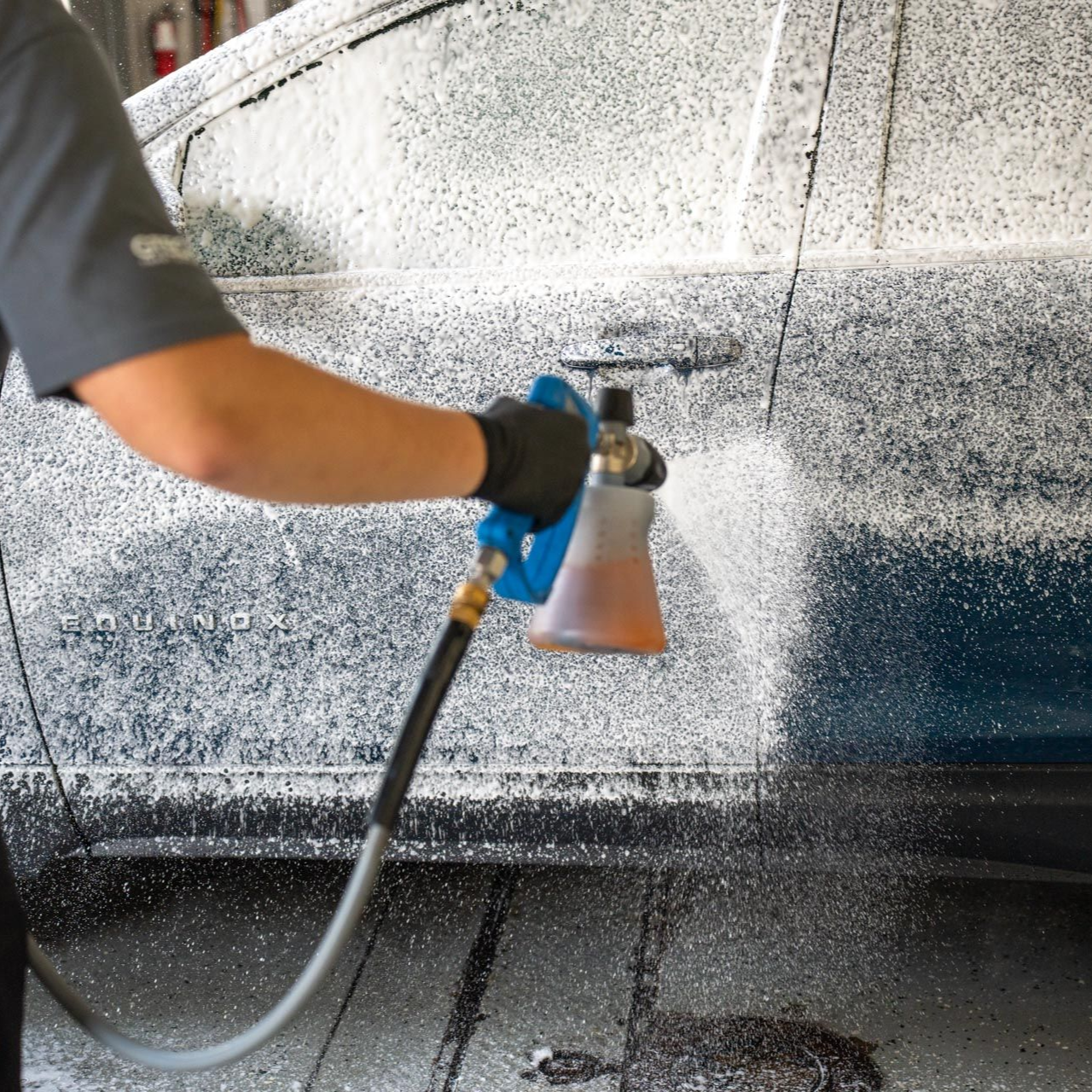 A person wearing blue gloves is cleaning the headlight of a car