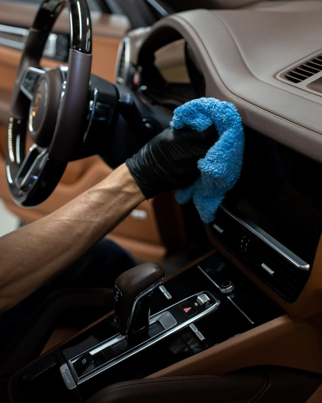 A car is being washed with a high pressure washer in a garage.