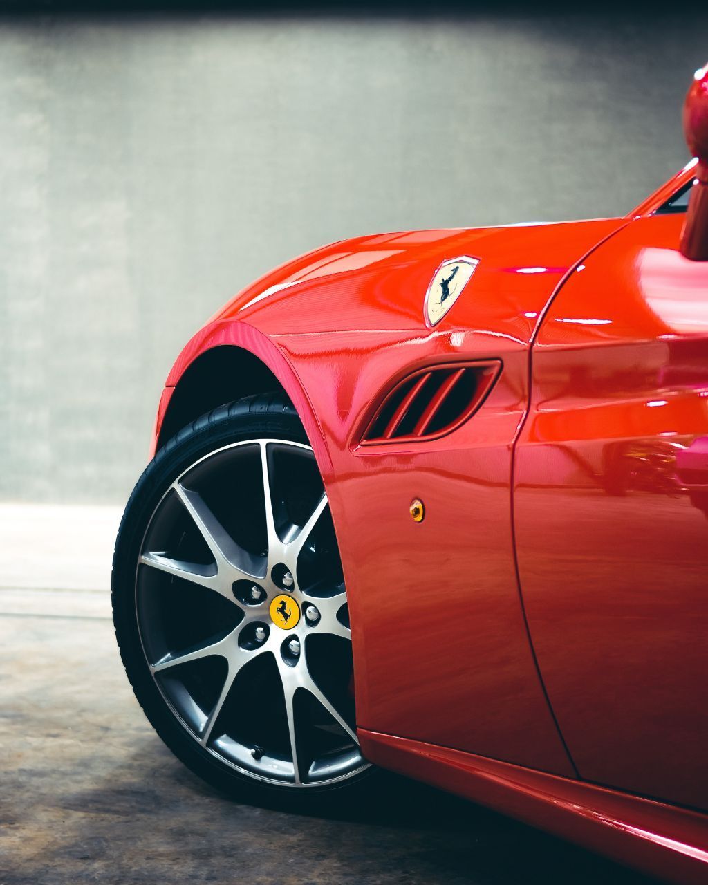 A car is being washed with a high pressure washer in a garage.