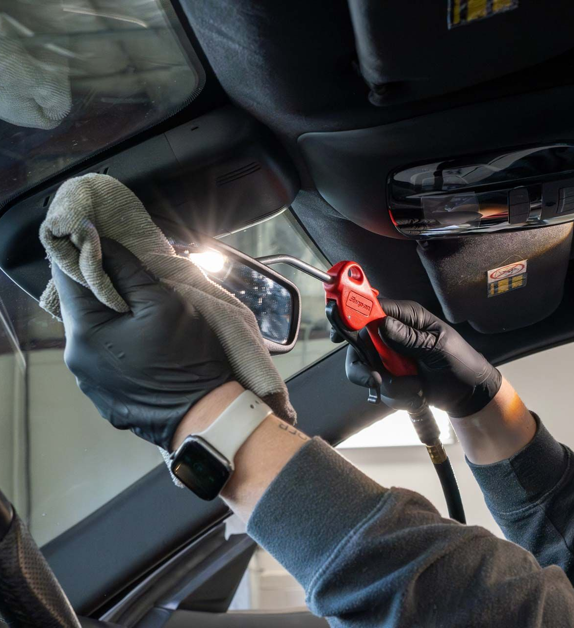 A person wearing blue gloves is cleaning the headlight of a car