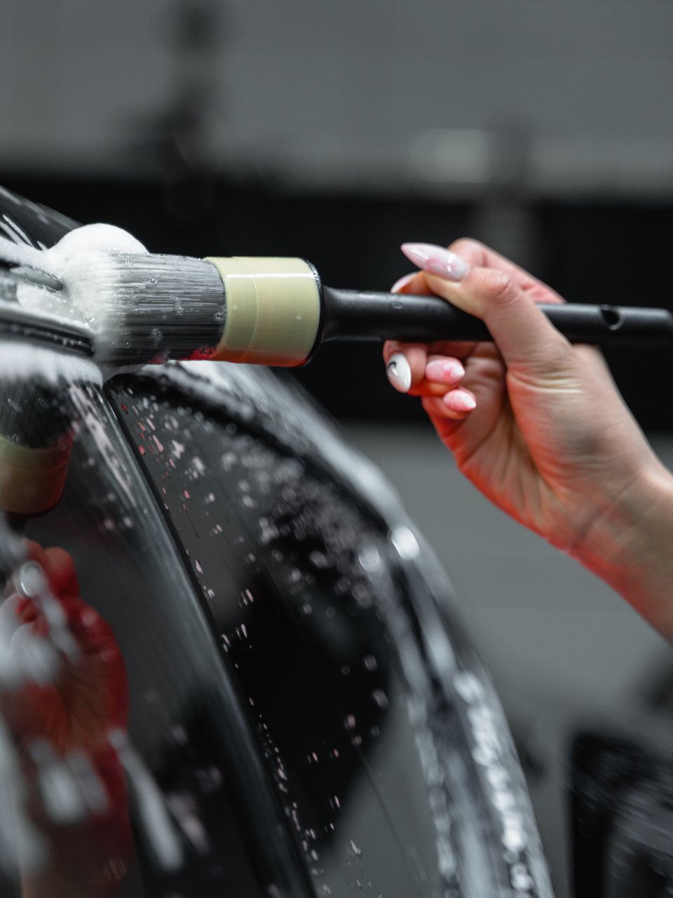A car is being washed with a high pressure washer in a garage.