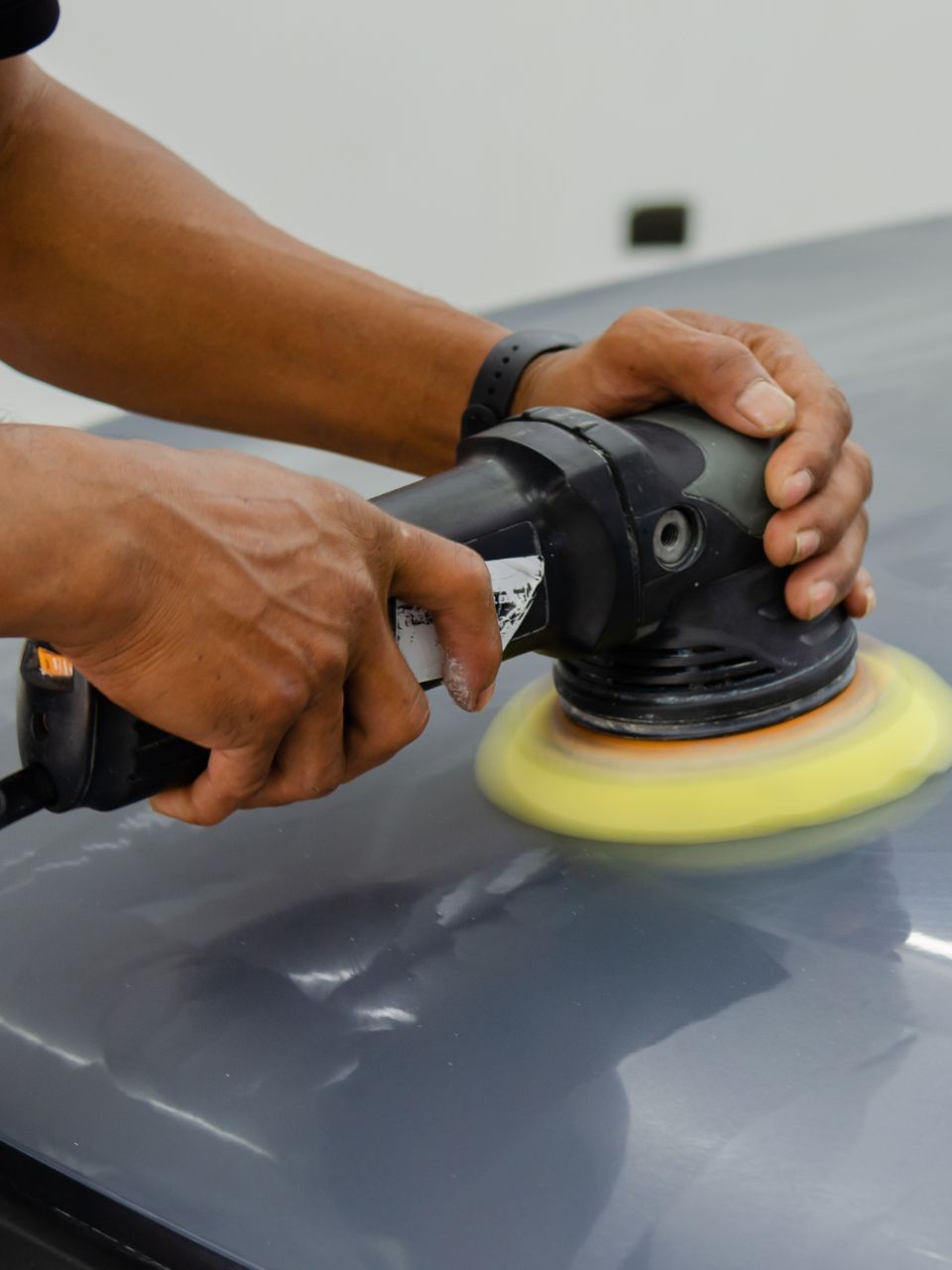 A car is being washed with a high pressure washer in a garage.