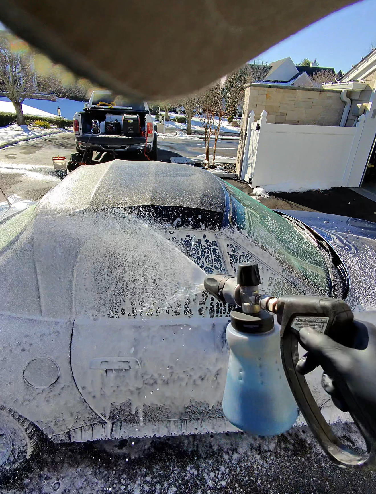 A car is being washed with a high pressure washer in a garage.