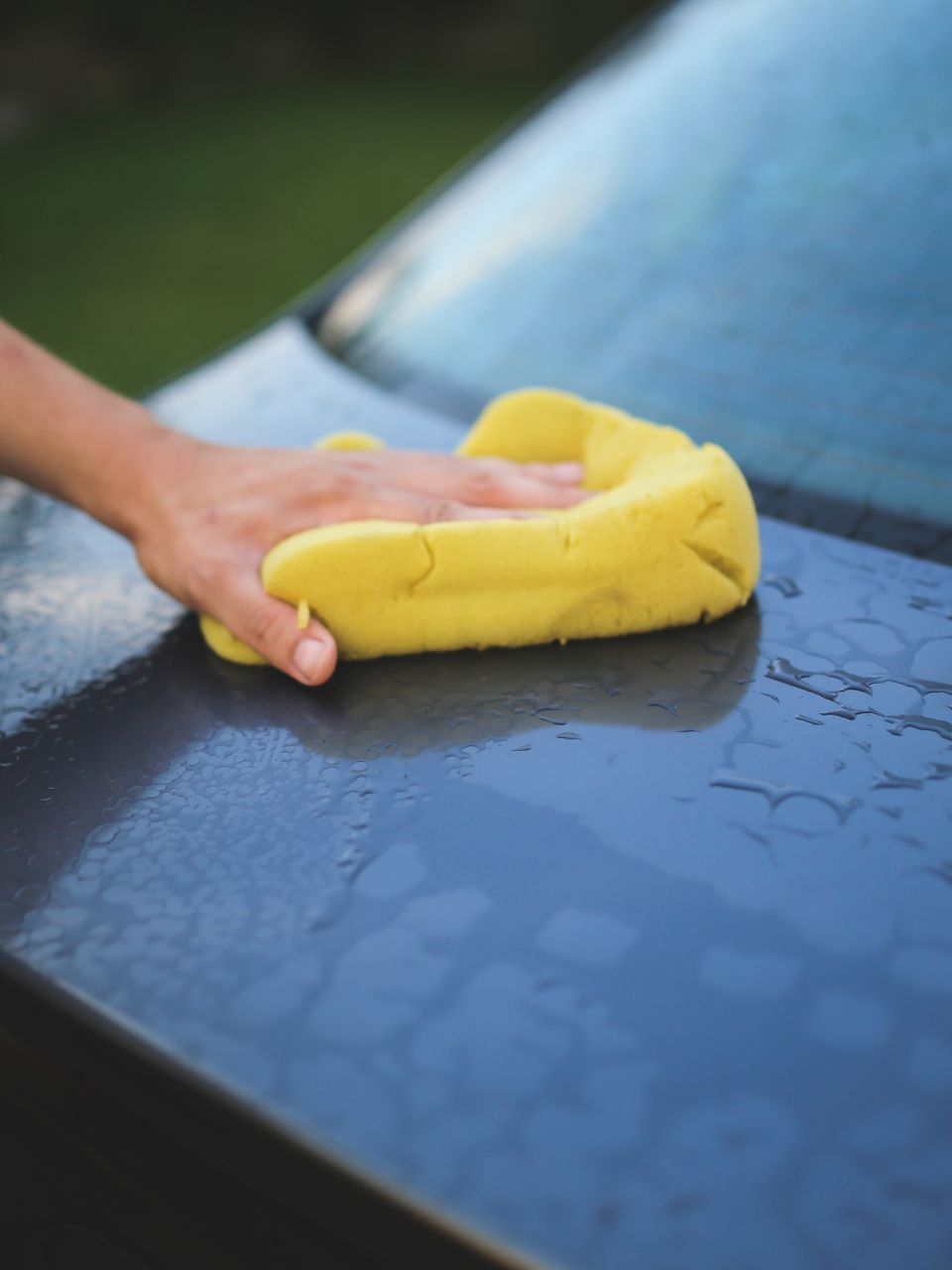 A car is being washed with a high pressure washer in a garage.