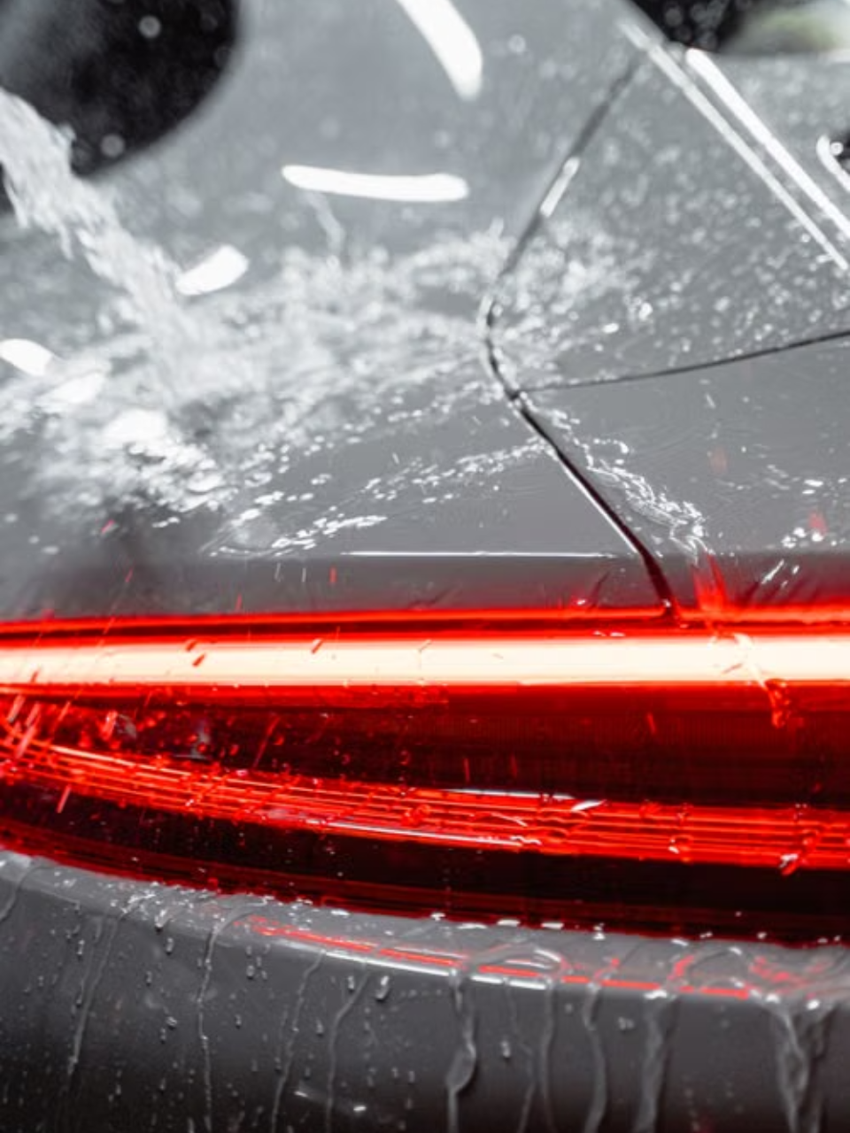 A car is being washed with a high pressure washer in a garage.