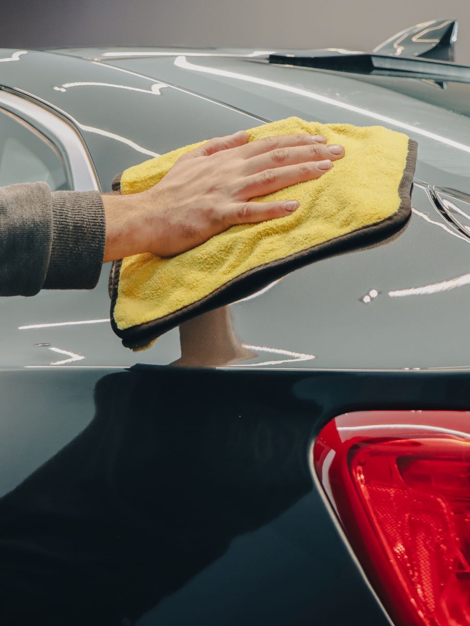 A car is being washed with a high pressure washer in a garage.