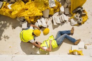 A construction worker is laying on the ground after a fall on a construction site.