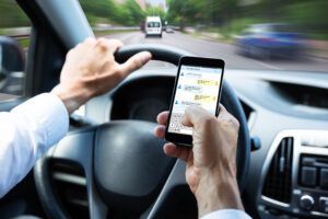 A man is driving a car and using a cell phone.