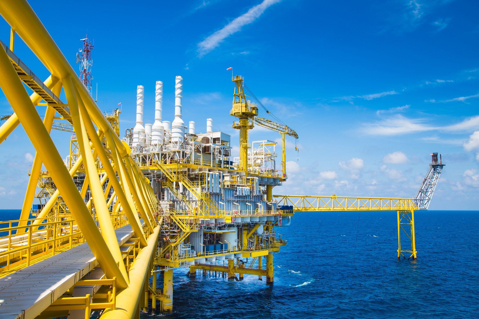 Offshore oil rig platform in a blue ocean under a bright sky.