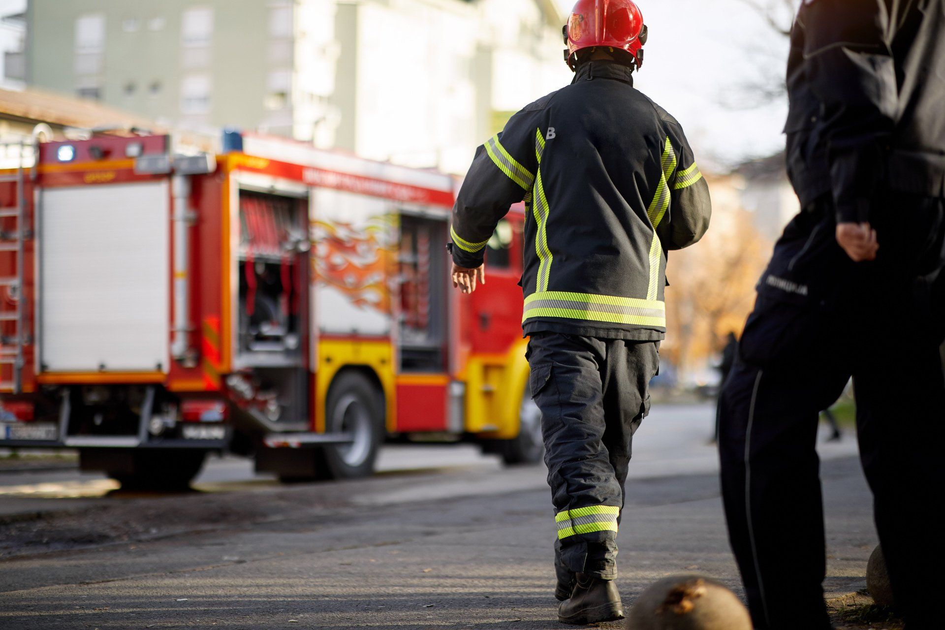 Firefighter in uniform running towards a fire truck, scene of emergency.