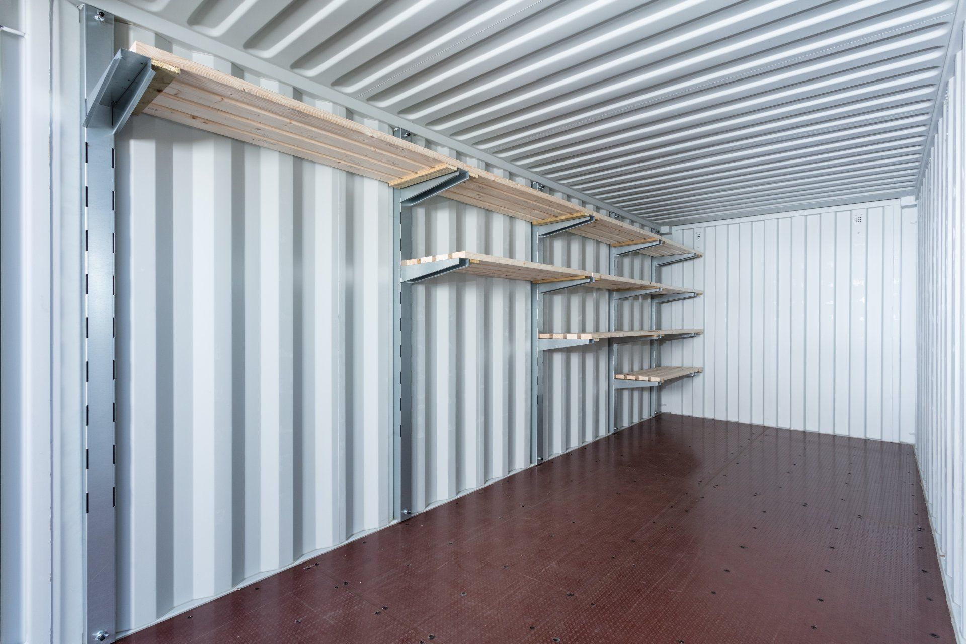 Storage container interior with shelves against a corrugated wall; brown floor.